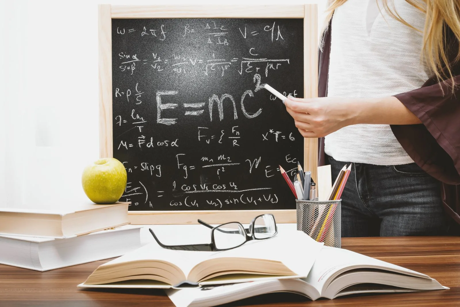 Frau schreibt Physikformeln an eine Tafel